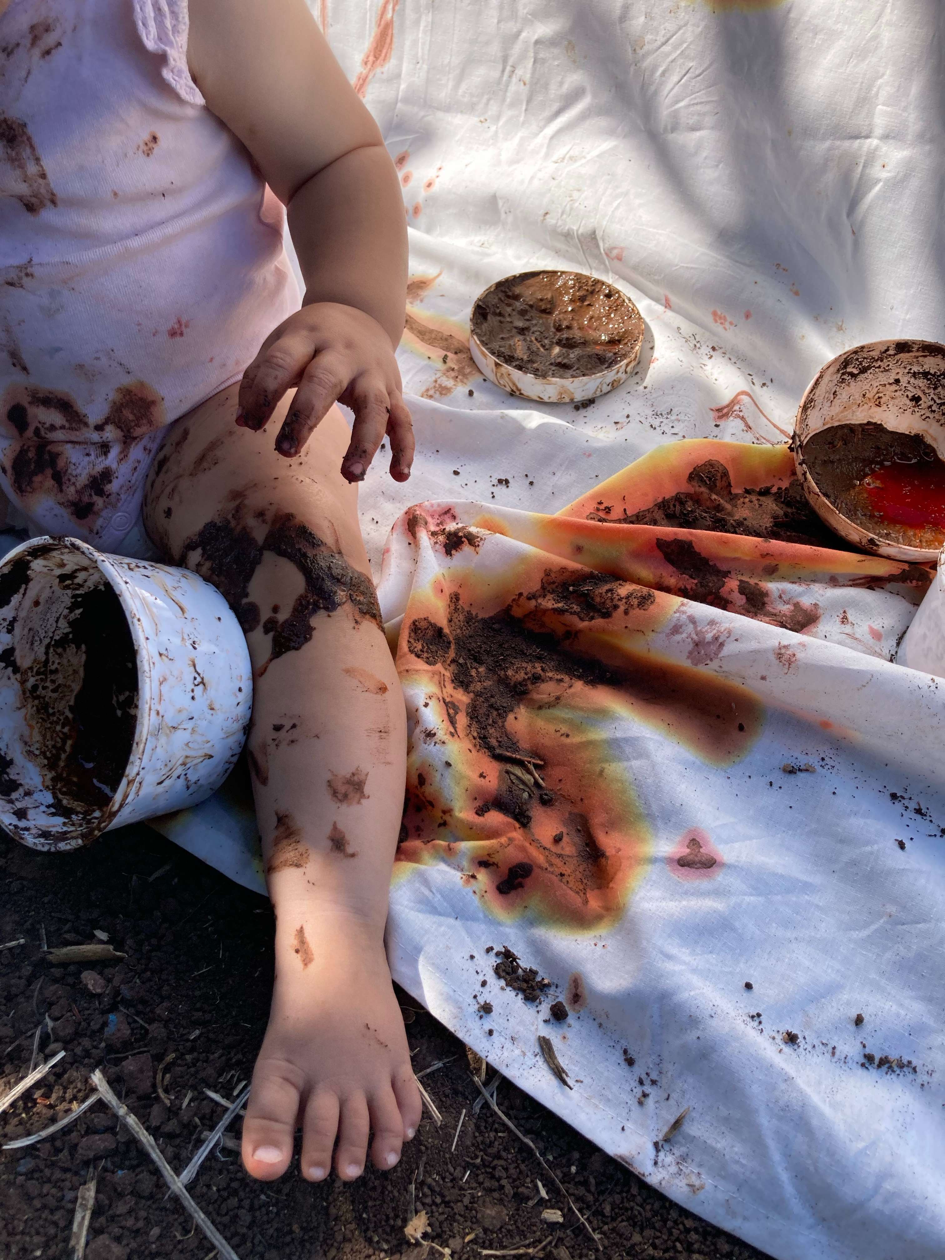 Criança explorando livremente com terra e materiais naturais